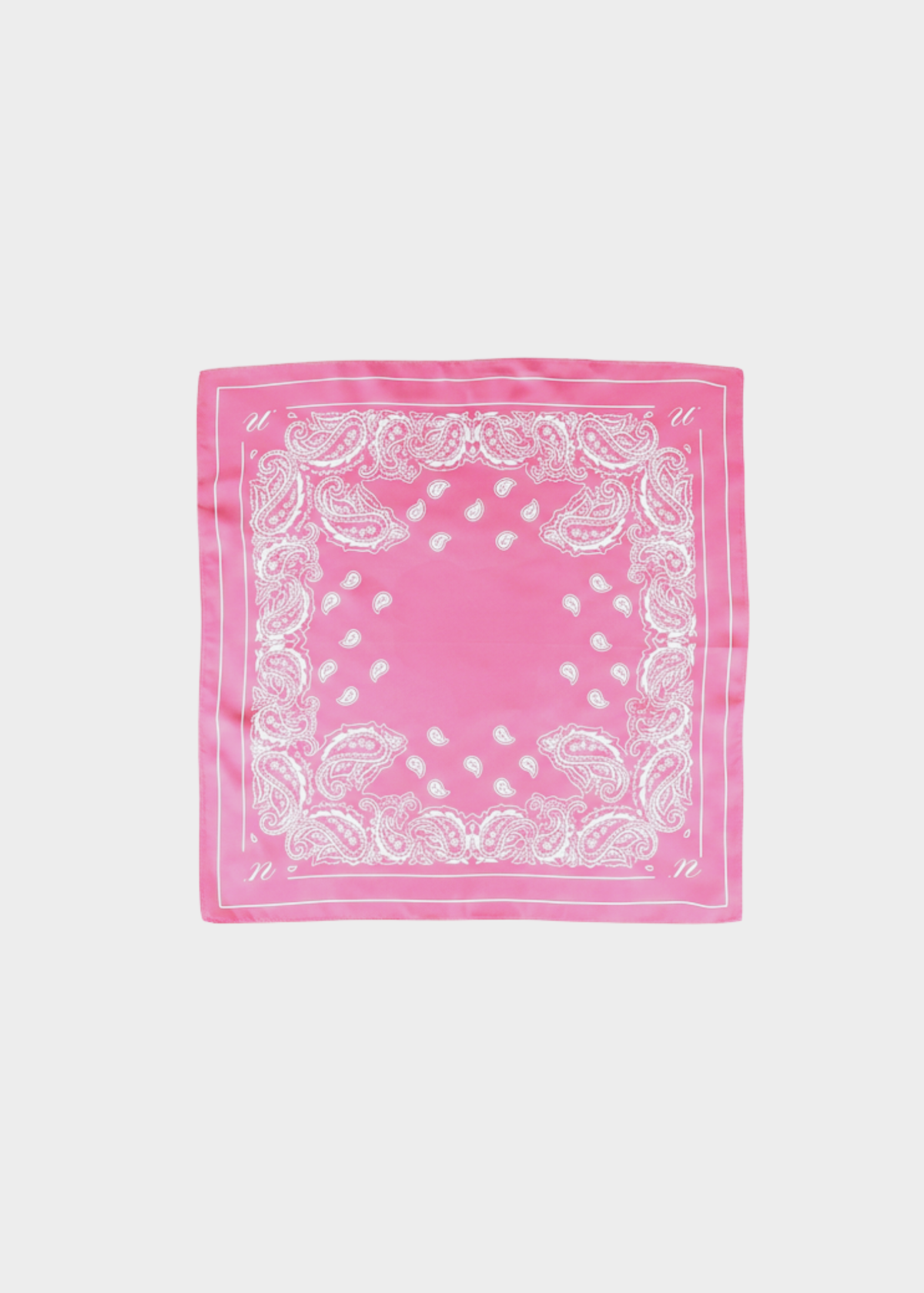 Noted Antwerp Alice scarf in pink. Rectangular scarf with with paisley print on pink 100% silk scarf.
A pink square bandana or scarf featuring a white paisley border pattern, laid flat against a light gray background.