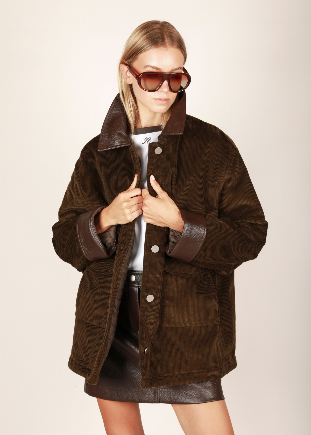 NOTED ANTWERP Boris coat - khaki leather. A brown corduroy jacket with a contrasting dark brown collar and cuffs, featuring a button-up front and two front flap pockets, shown flat on a light gray background. Our Boris coat in khaki is a fall winter staple. Featuring a brown leather collar and double patched pockets.