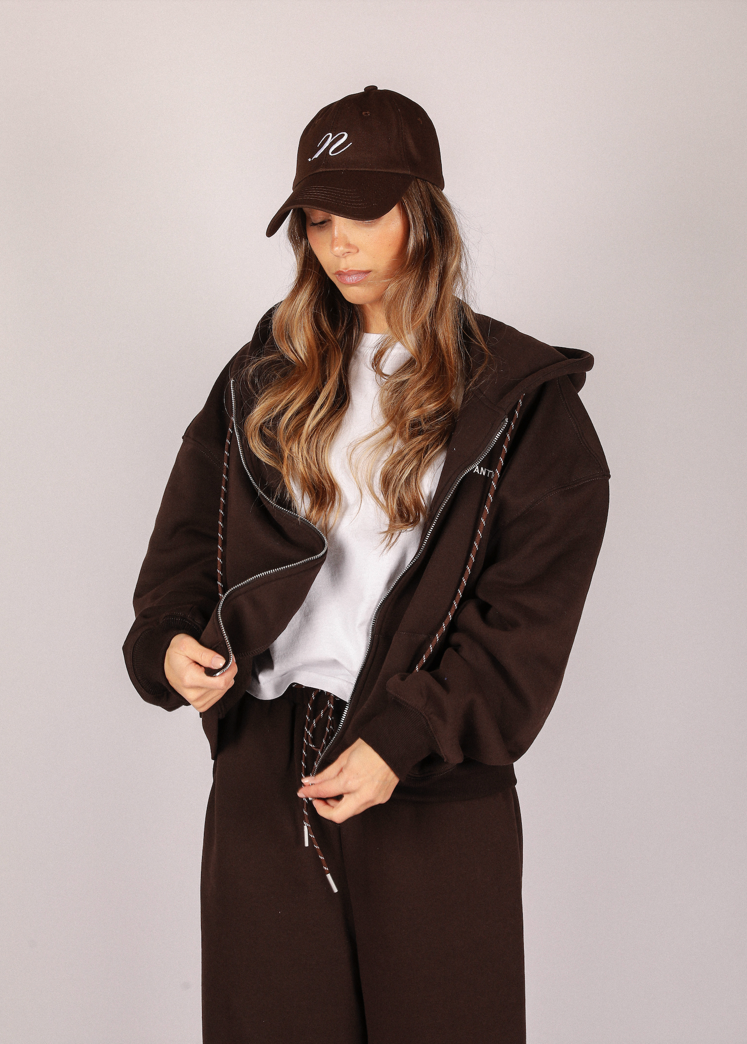 Person wearing a brown coat and cap on a plain background