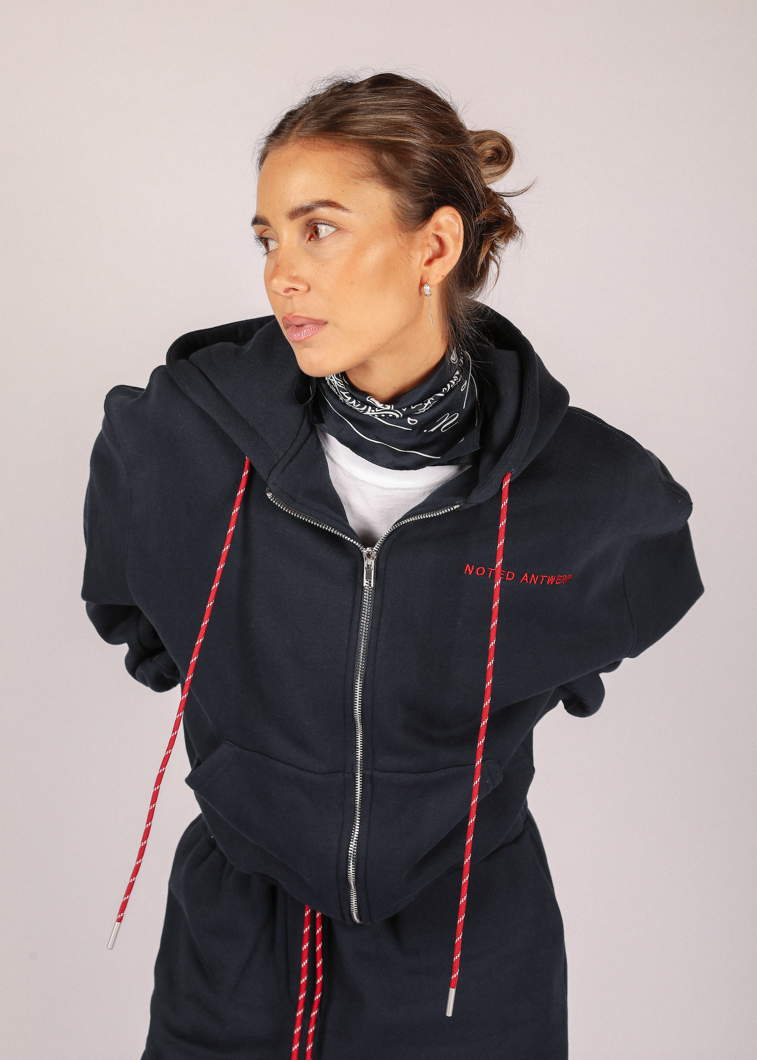 Person wearing a dark blue hoodie with red drawstrings on a light gray background