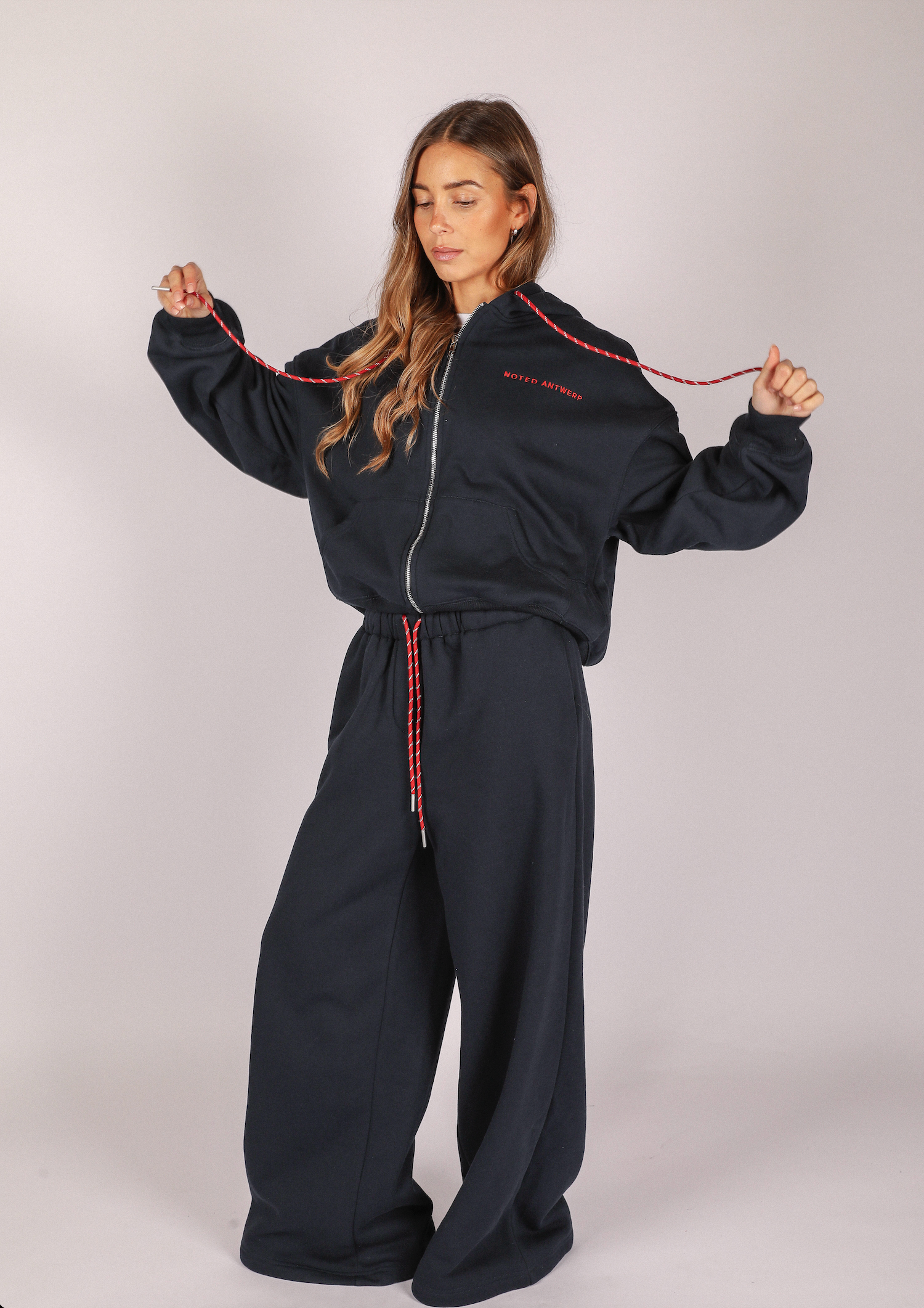 Person wearing a dak blue jumpsuit with red accents on a plain background