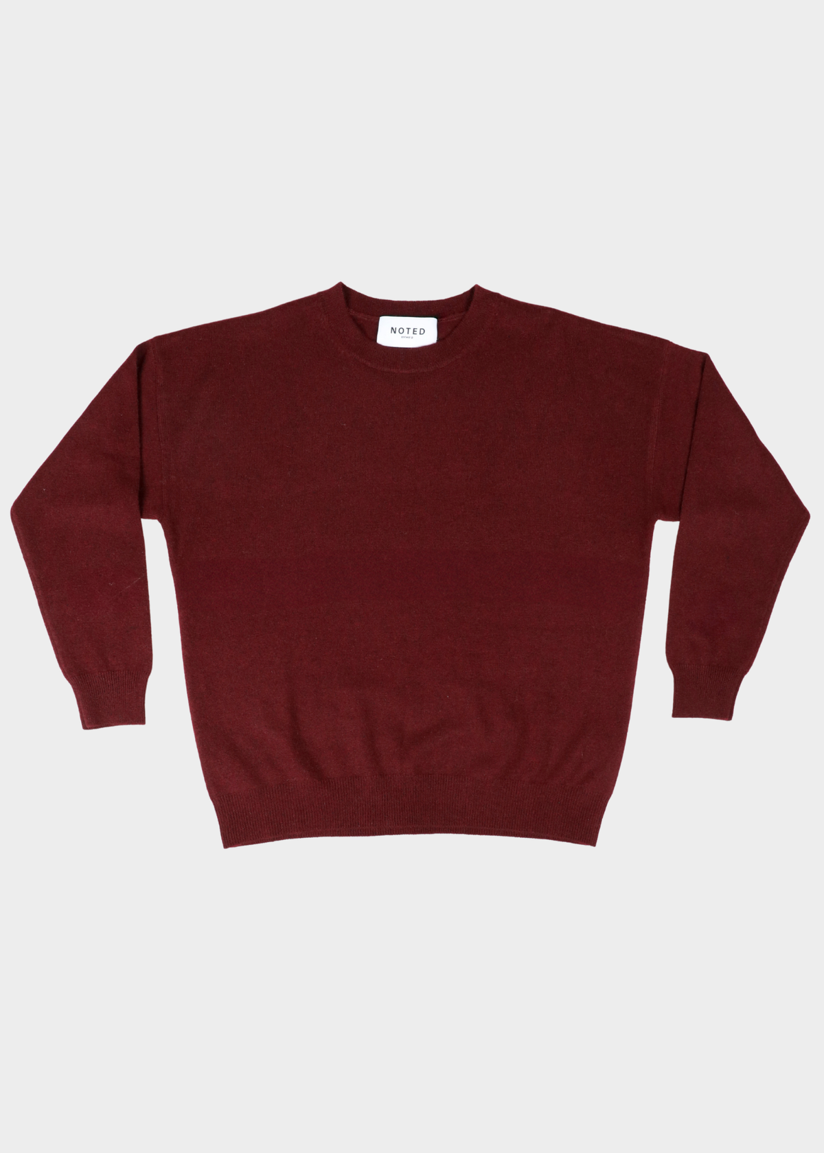 A dark burgundy crewneck sweater laid flat against a light gray background. The brand name 'NOTED ANTWERP' is visible on the inner neck label.