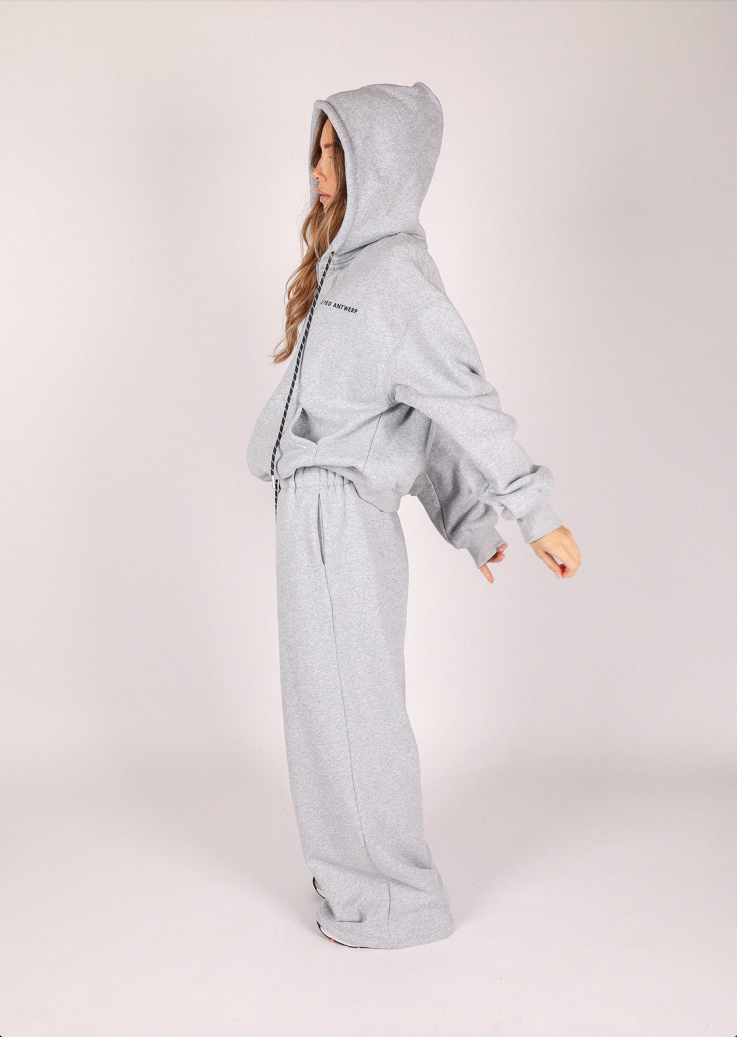 Person wearing a gray hoodie and pants on a white background