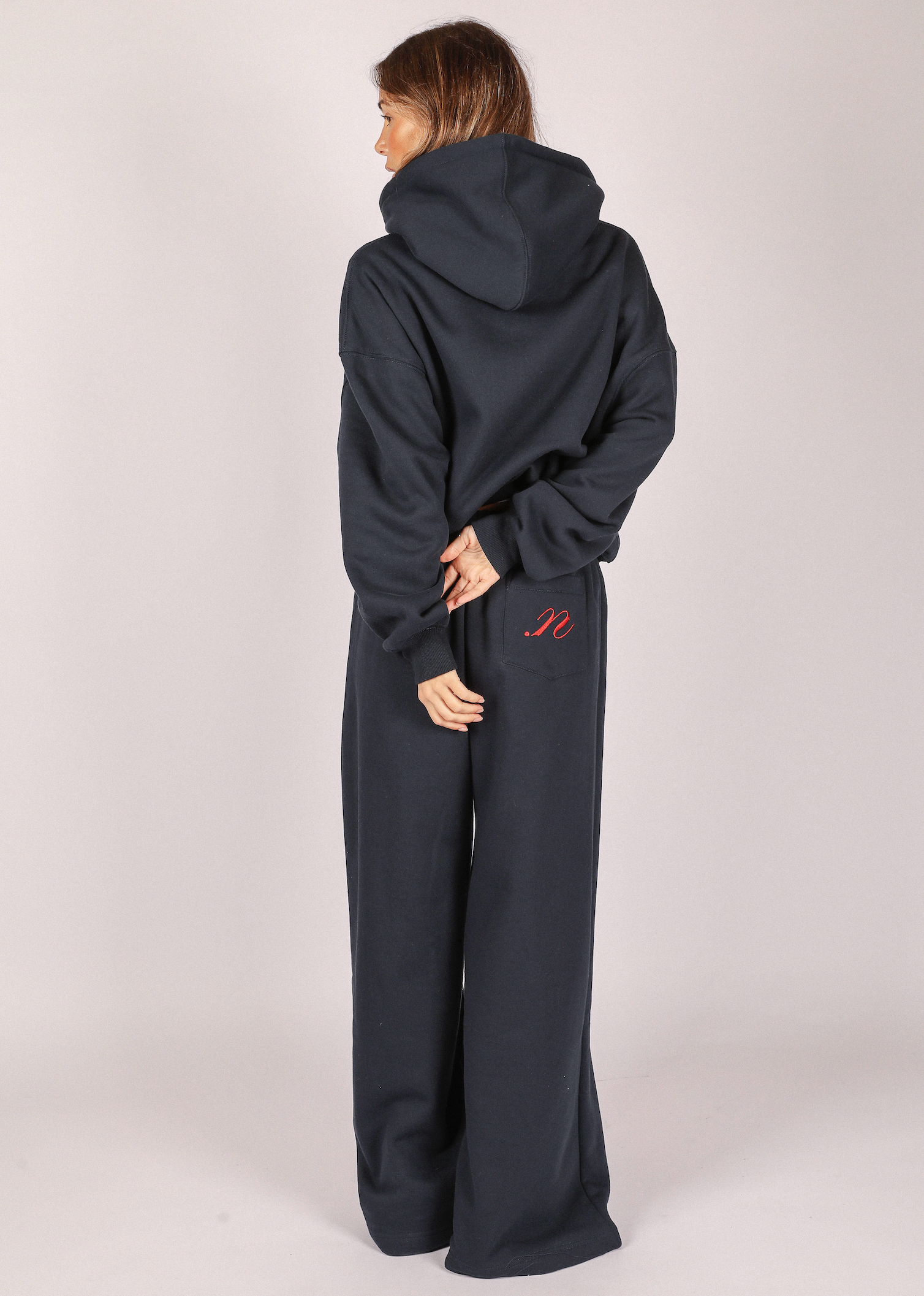 Person wearing a navy hoodie and pants with a noted antwerp logo 