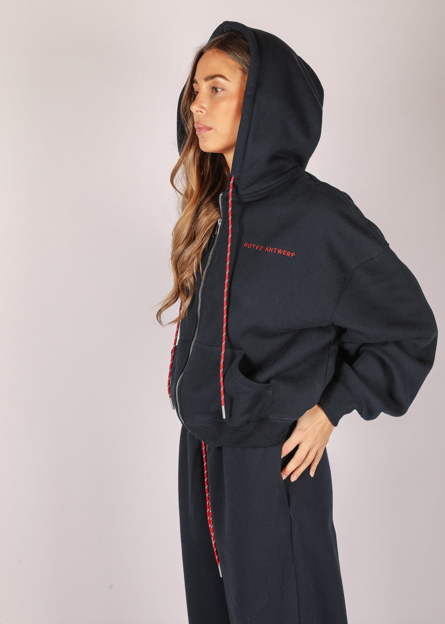 Person wearing a dark blue hoodie with red accents on a plain background