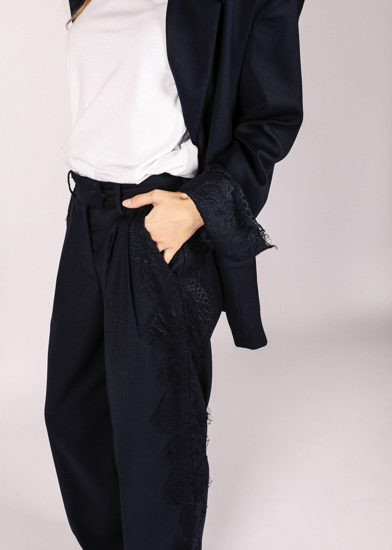 Person wearing a navy blue blazer from noted antwerp with lace details on a white background
